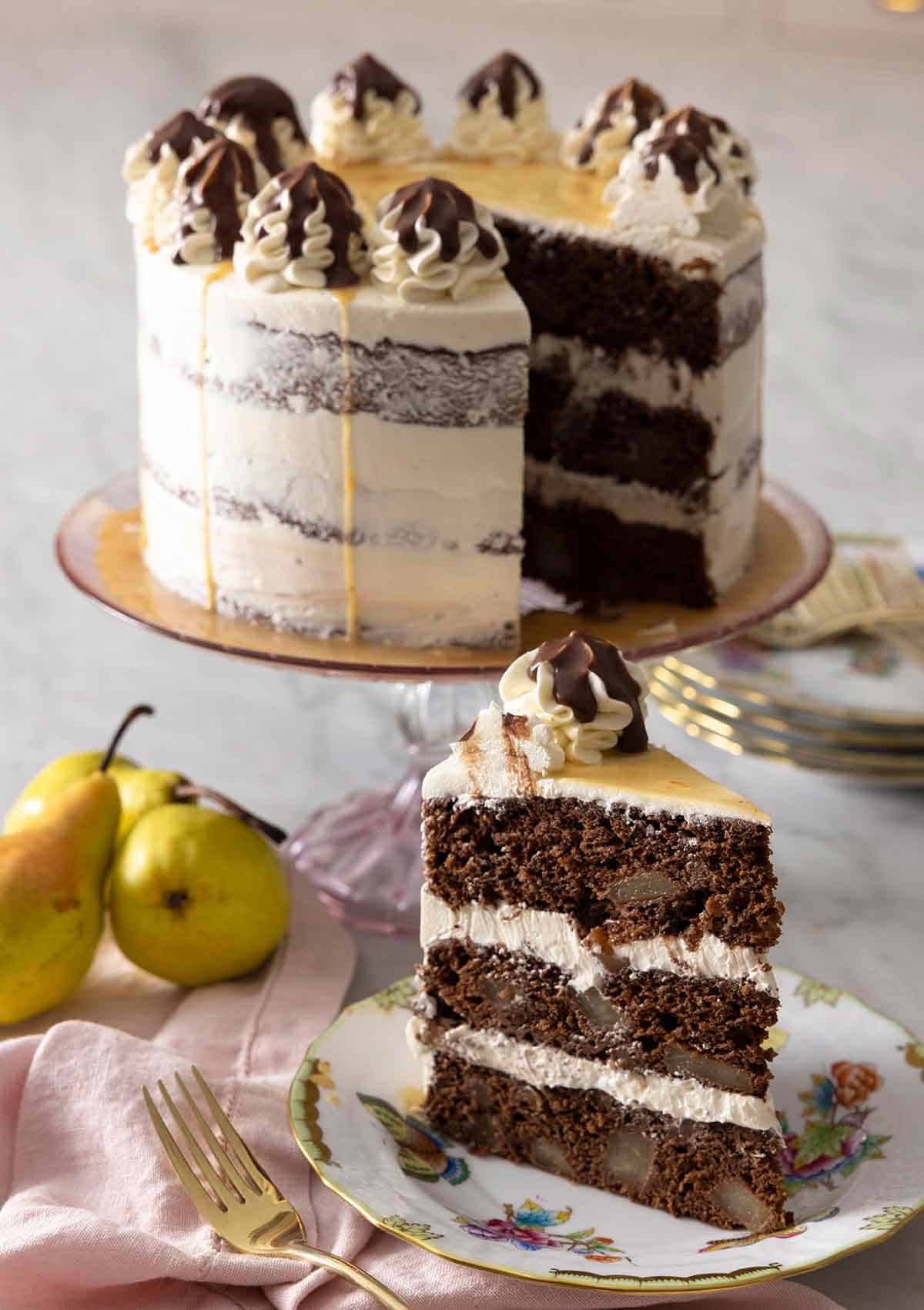 A chocolate pear cake on a cake stand with a slice in front.