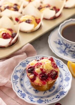 A plate with a cranberry orange muffin with more in the back.