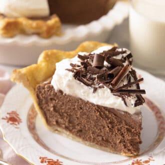 A slice of French silk pie on a plate in front of a cup of milk.