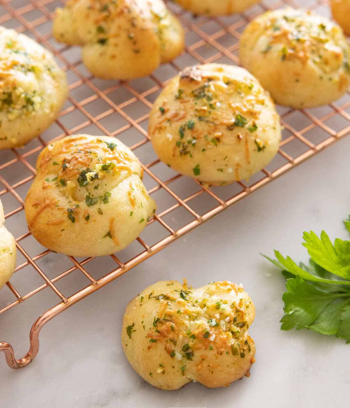 A wire rack of garlic knots with one in front.