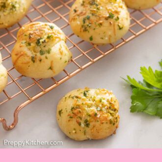 Pinterest graphic of a wire rack with garlic knots with one in front.