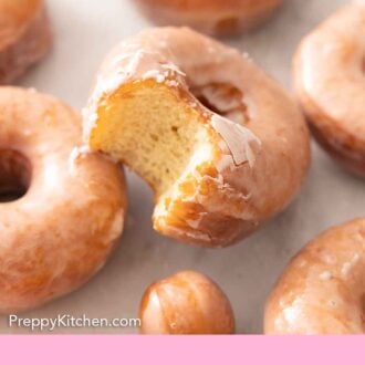 Pinterest graphic of multiple glazed donuts, one with a bite taken out.