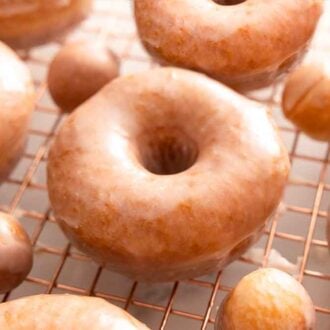 Glazed donuts and donut holes on a cooling rack.
