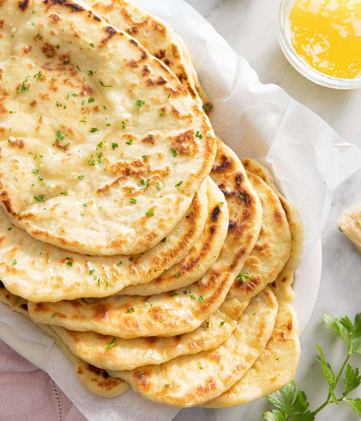 A stack of naan bread in a parchment lined platter.
