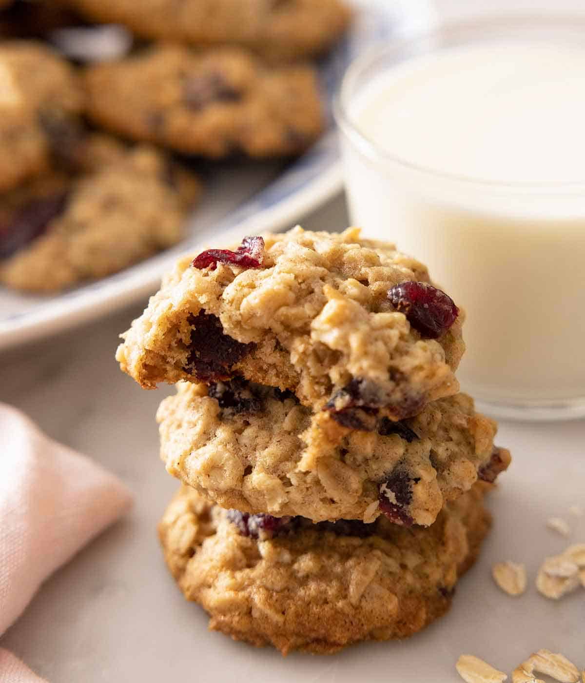 A stack of three oatmeal cranberry cookies with a bite taken from the top cookie.