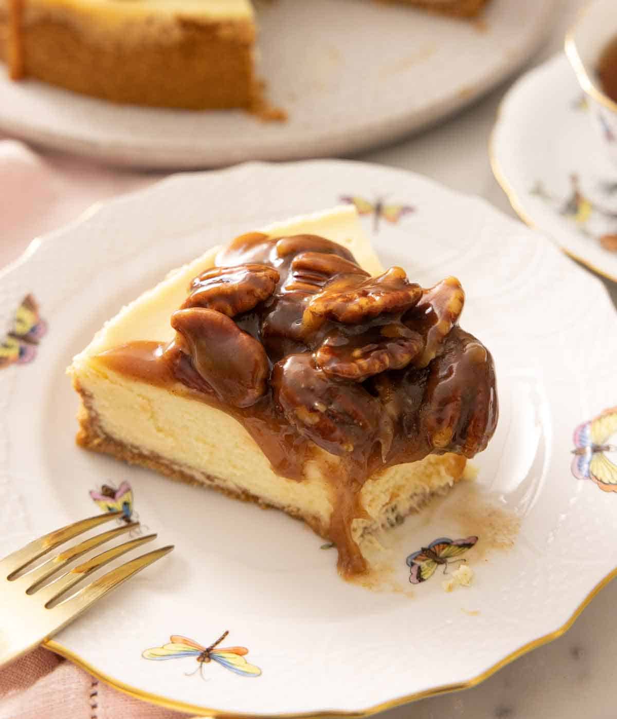 A slice of pecan pie cheesecake on a plate with a bite taken out.