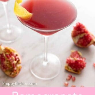 Pinterest graphic of a pomegranate martini with fresh pomegranate scattered around.