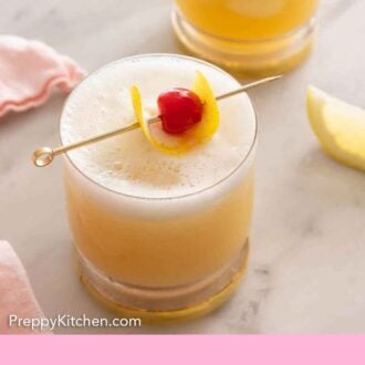 Pinterest graphic of two cocktail glasses of whiskey sours with lemon peel and a maraschino cherry on top.