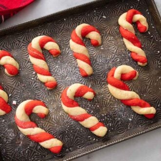 A baking tray with multiple candy cane cookies.