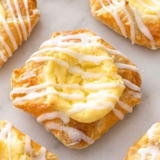 Multiple cheese danishes on a marble surface.