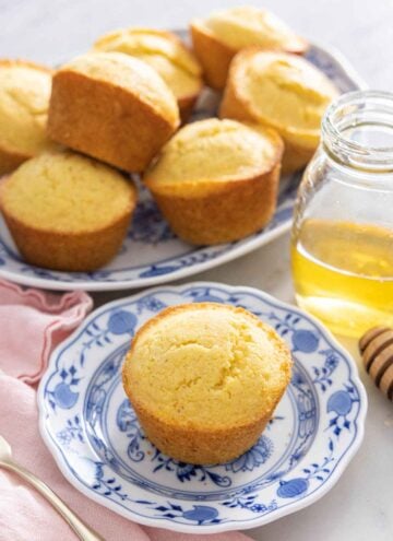 A platter of cornbread muffins with one in front on a plate.