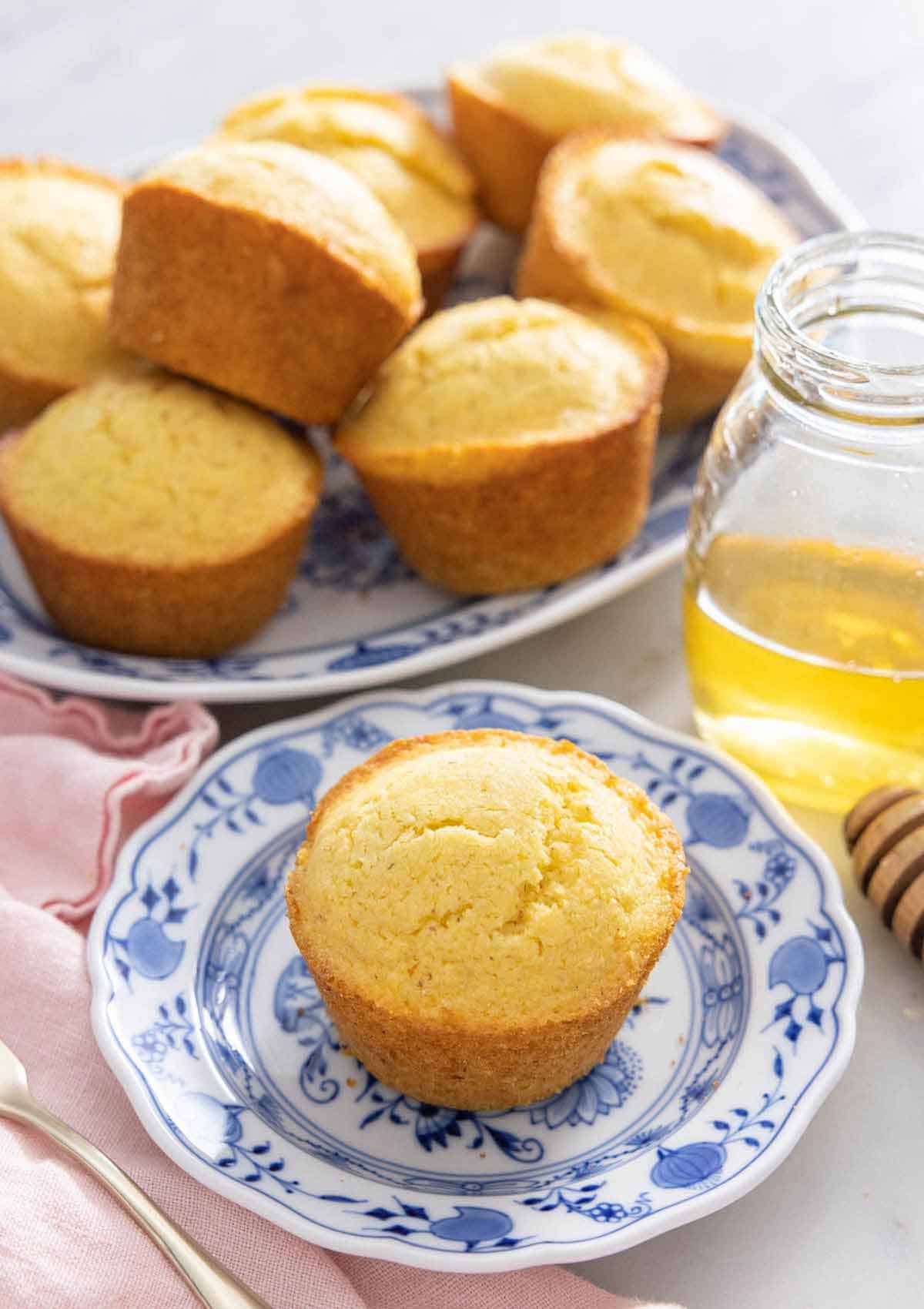 A platter of cornbread muffins with one in front on a plate.