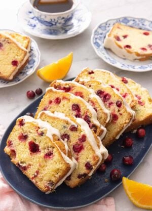 A platter with sliced cranberry orange bread with fresh fruit around it.