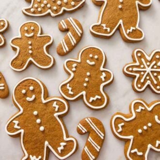 Multiple decorated gingerbread cookies on a marble surface.