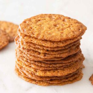 A stack of lace cookies with a couple scattered around.