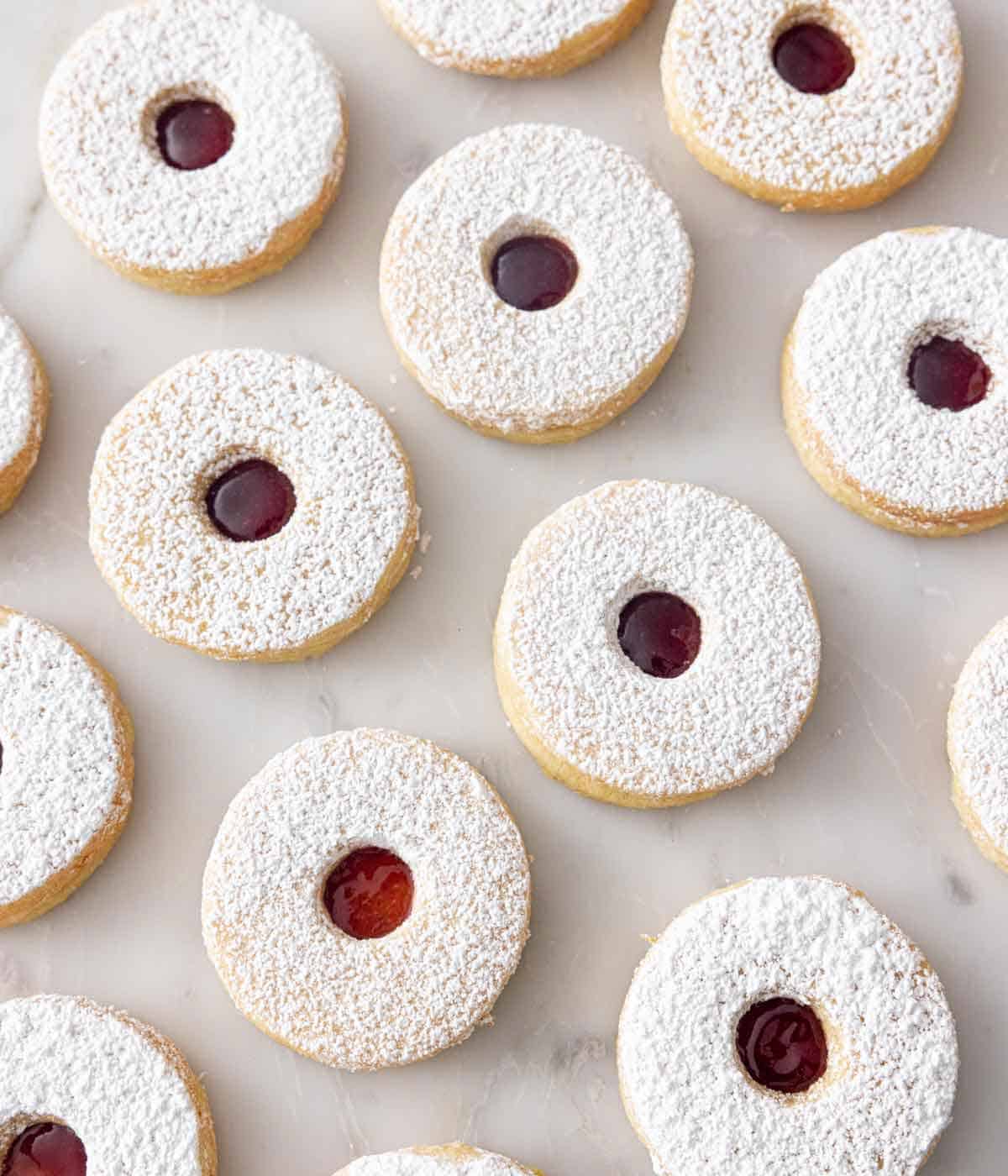 Multiple linzer cookies in a single layer on a white surface.