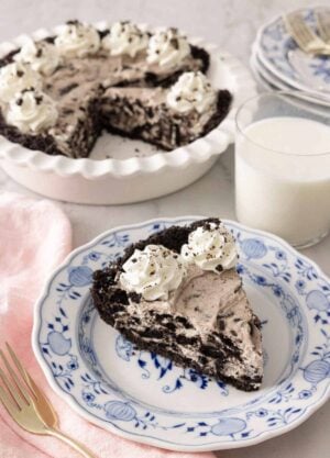 A slice of Oreo pie in front of a glass of milk and baking dish.
