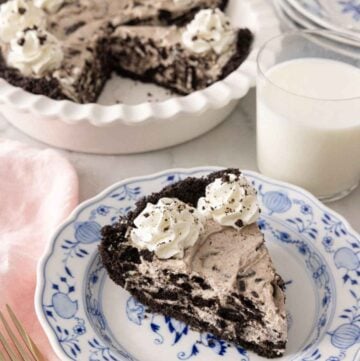 A slice of Oreo pie in front of a glass of milk and baking dish.