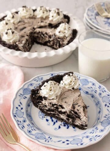 A slice of Oreo pie in front of a glass of milk and baking dish.