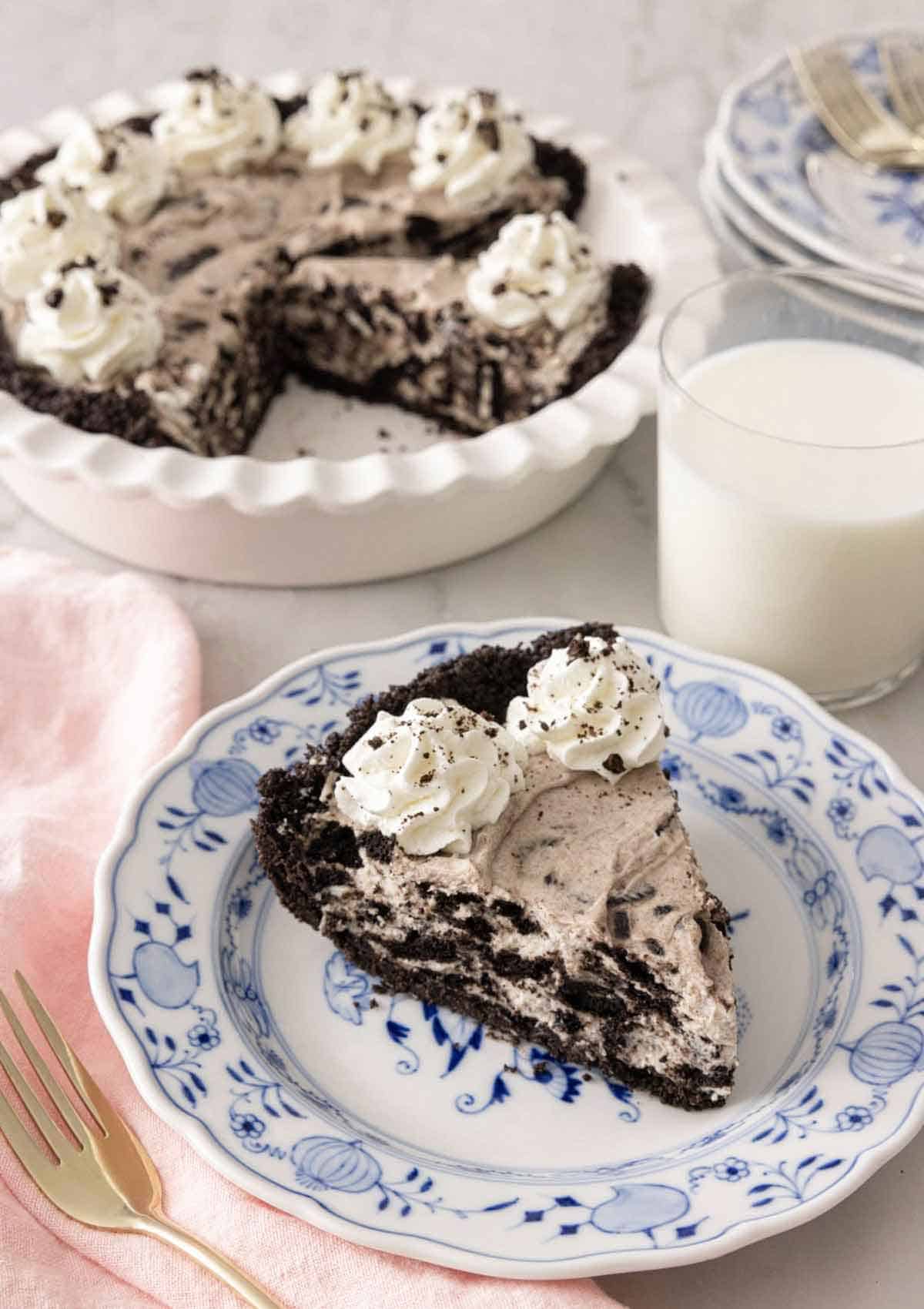 A slice of Oreo pie in front of a glass of milk and baking dish.