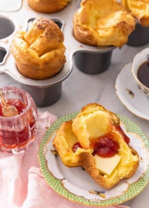 Half of a popovers with butter and jam spread in the middle.