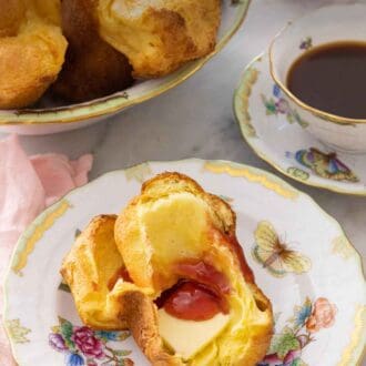 Pinterest graphic of a plate with half a popover with butter and jam on it.