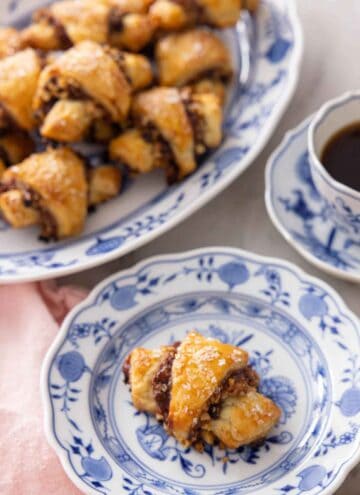 A plate with a rugelach in front of a platter with more.