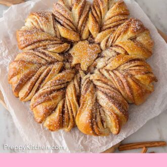 Pinterest graphic of a star bread with sugar dusted on top on a sheet of parchment.