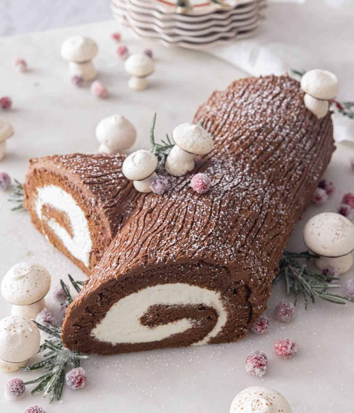 A Yule log cake with meringue mushrooms and sugared rosemary and cranberries.