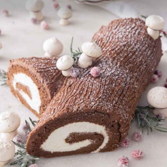 Pinterest graphic of a Yule log with meringue mushrooms, sugared rosemary, and cranberries.