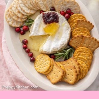 Pinterest graphic of a baked brie cut opened on a platter with cheese melting out by the crackers.