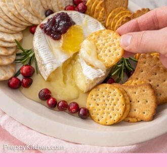 Pinterest graphic of a cracker scooping out baked brie from the cheese platter.