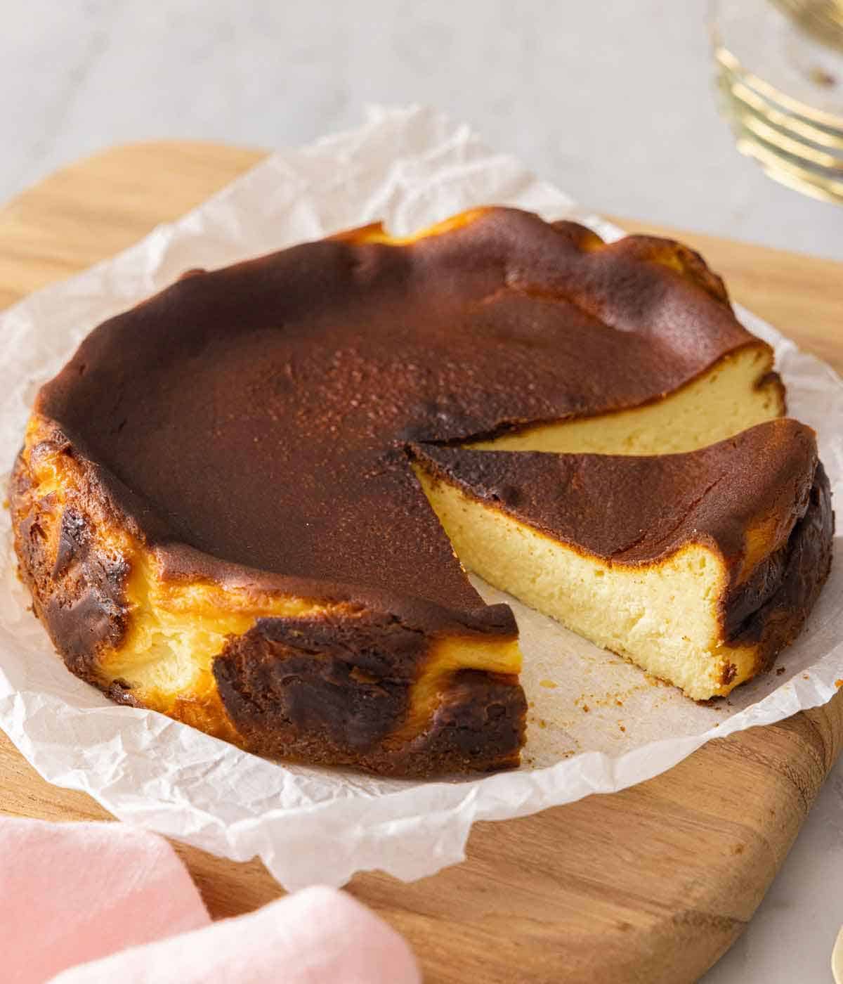 A basque cheesecake with a slice cut out and another cut but not removed.