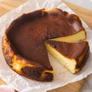 A basque cheesecake with a size cut out and another slice still attached.