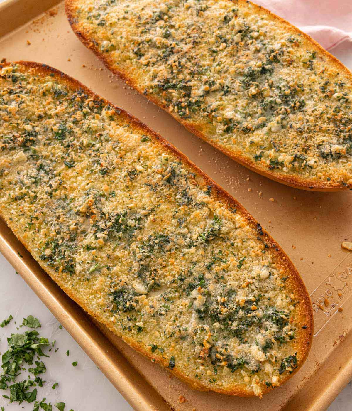 Two pieces of garlic bread on a sheet pan.