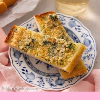 Pinterest graphic of two pieces of garlic bread on a plate by a glass of wine.
