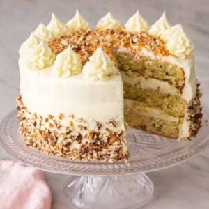 A cake stand with an Italian cream cake with a slice cut out.