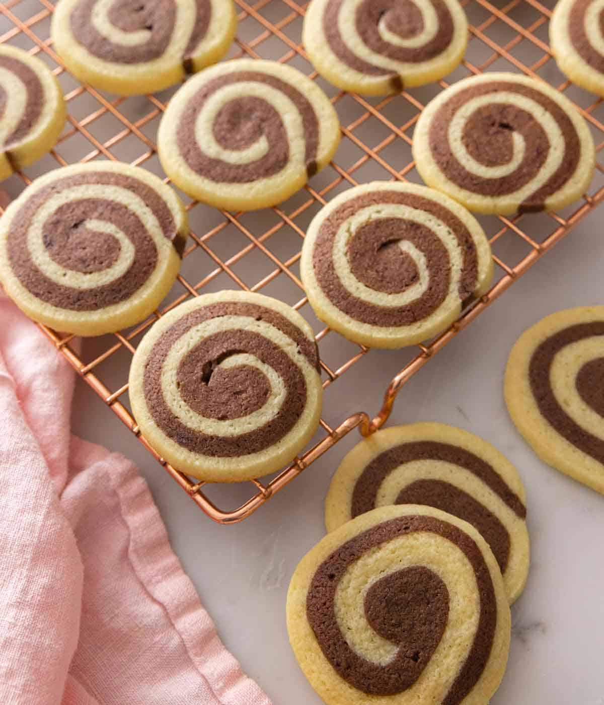 A cooling rack with multiple pinwheel cookies in a single layer.
