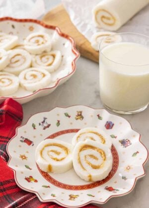 A plate with three pieces of potato candy by a glass of milk.