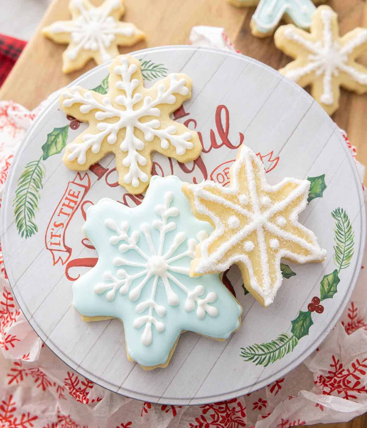 A plate with three snowflake cookies with different decorative icing.