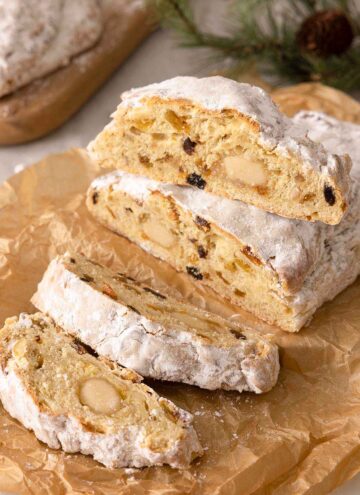 A loaf of stollen, sliced on parchment paper.