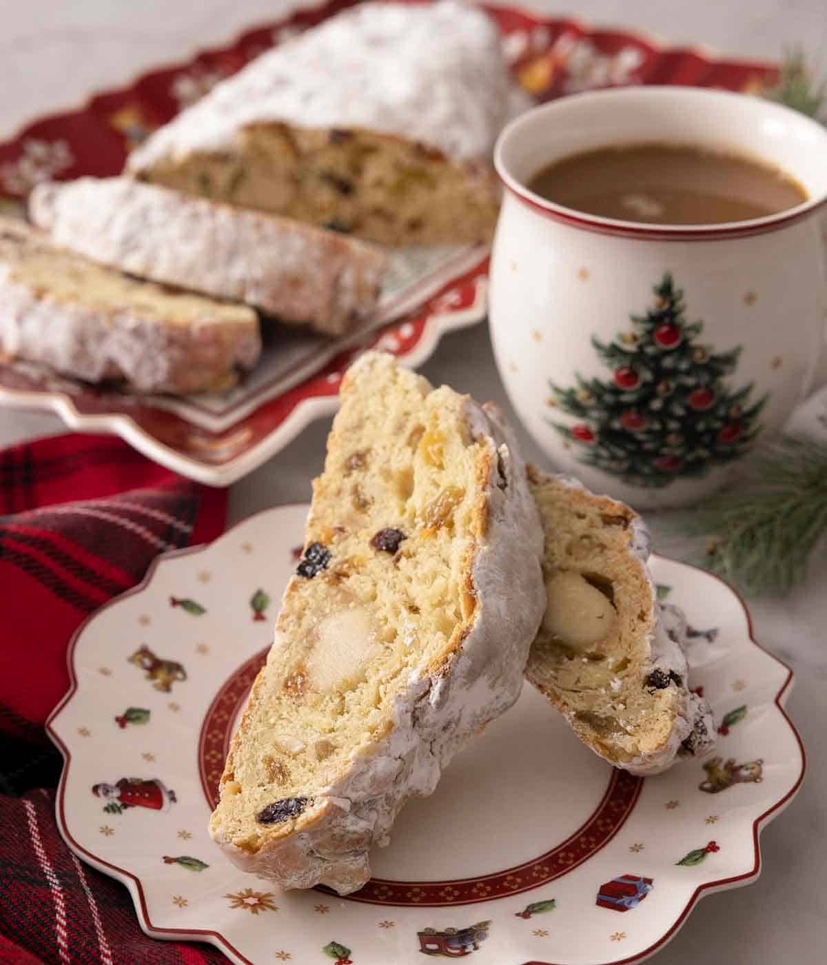 A plate with two slices of stollen by a mug of hot chocolate.