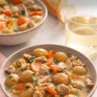 Pinterest graphic of a bowl of chicken stew by a glass of wine.