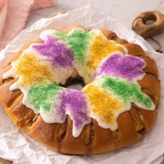 A colorful king cake on a parchment-lined serving board.