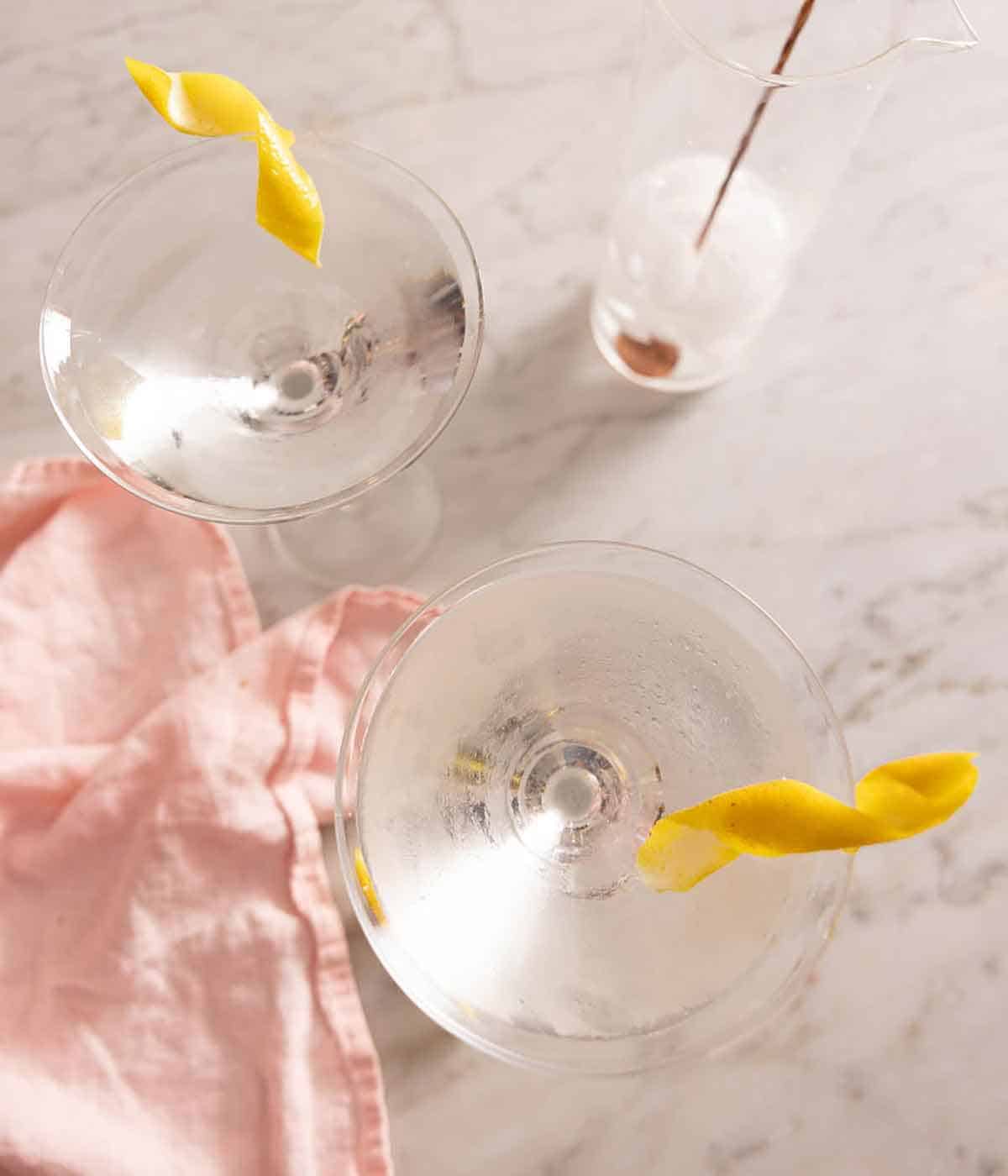 Overhead view of two glasses of martinis with lemon garnishes.