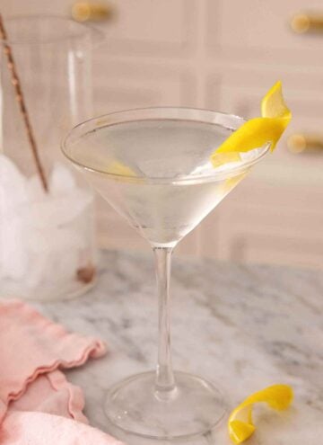 A glass of martini with a lemon twist garnish.