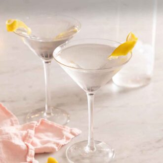 Pinterest graphic of two glasses of martinis with lemon garnishes.