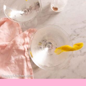 Pinterest graphic of an overhead view of two glasses of martinis with lemon twist garnishes.