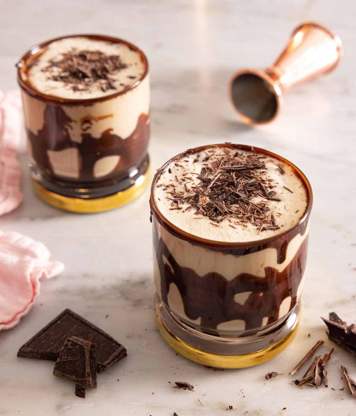 Two glasses of mudslides with shaved chocolate on top and scattered around.