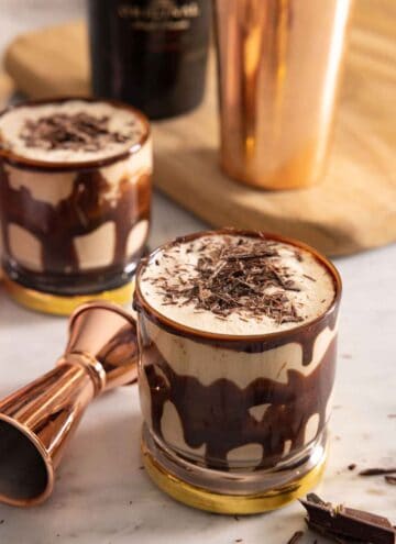 Two glasses of mudslide with shaved chocolate on top.